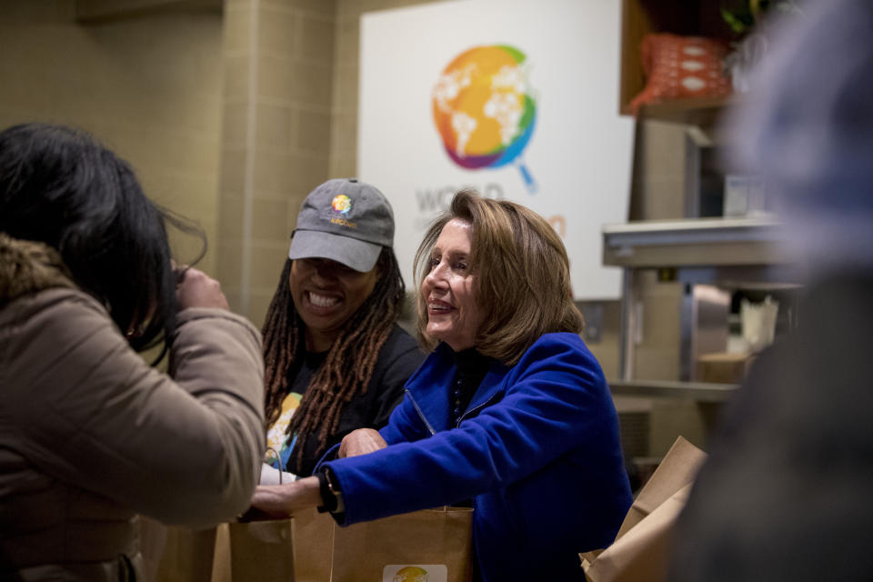 House Speaker Nancy Pelosi of Calif., center, smiles as she helps give out food at World Central Kitchen, the not-for-profit organization started by Chef Jose Andres, Tuesday, Jan. 22, 2019, in Washington. The organization devoted to providing meals in the wake of natural disasters, has set up a distribution center just blocks from the U.S. Capitol building to assist those affected by the government shutdown. (AP Photo/Andrew Harnik)