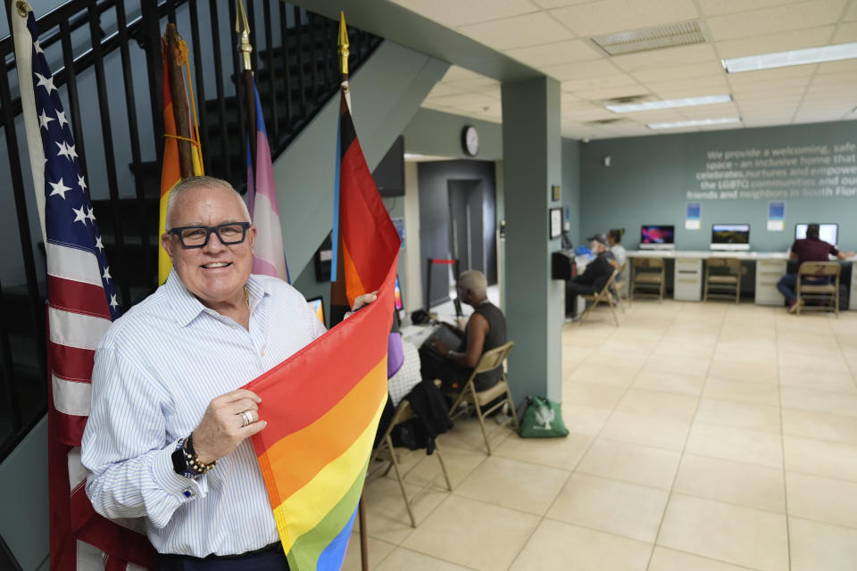 Robert Boo, CEO of the Pride Center at Equality Park, poses with a rainbow flag inside the community center supporting the local LGBTQ+ community and their allies, Wednesday, Jan. 17, 2024, in Wilton Manors, Fla. A bill moving forward in the Florida State House would ban the display of any flag deemed political in government buildings. The legislation is seen as another anti-LGBTQ+ bill in a state that has passed several under Republican Gov. Ron DeSantis. (AP Photo/Rebecca Blackwell)