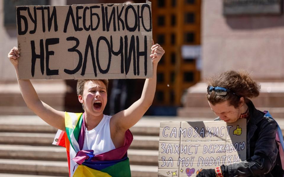 Participants hold placards as they attend a rally against discrimination of the LGBT+ community, amid Russia's attack on Ukraine, in Kyiv, Ukraine, May 17, 2024. A slogan reads, "It's not a crime to be a lesbian".