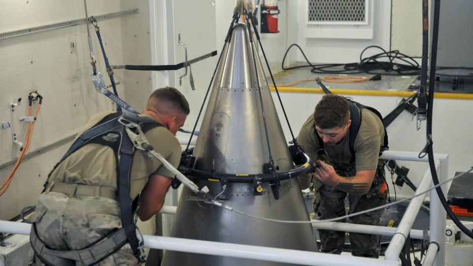 Senior Airman Jacob Deas, 23, left, and Airman 1st Class Jonathan Marrs, 21, right, secure the titanium shroud at the top of a Minuteman III intercontinental ballistic missile on Aug. 24, 2023, at the Bravo 9 silo at Malmstrom Air Force Base in Montana. (John Turner/Air Force via AP)