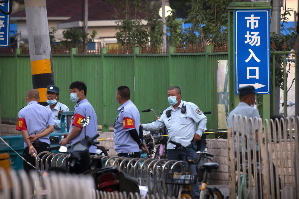 Security officials stand outside the entrance to a building holding a beef and lamb market in Beijing that was closed by authorities after it was visited by a person who tested positive for COVID-19, Friday, June 12, 2020. Local authorities announced on Thursday a 52-year-old man had become the city's first confirmed case of local transmission in weeks after he arrived at a clinic complaining of fever. The official Xinhua News Agency said two other cases of COVID-19 were confirmed in Beijing on Friday. (AP Photo/Mark Schiefelbein)