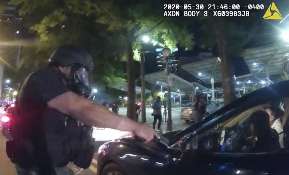 In this Saturday, May 30, 2020, photo taken from police body camera video released by the Atlanta Police Department, an officer points his handgun at Messiah Young while the college student is seated in his vehicle, in Atlanta. The following day, Atlanta's mayor two police officers were fired and three others placed on desk duty over excessive use of force during the arrest of Young and fellow college student Taniyah Pilgrim, seated in the passenger side of the car. (Atlanta Police Department via AP)