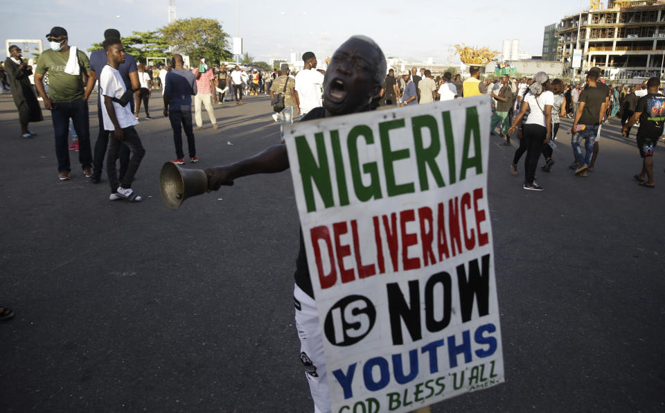 A man holds a sign as he demonstrates on the street to protest against police brutality in Lagos, Nigeria, Sunday Oct. 18, 2020. Nigerian protests against police brutality continued Sunday for the eleventh day, with demonstrators fending off attacks from gangs suspected to be backed by the police, warnings from the Nigerian military, and a government order to stop because of COVID-19. (AP Photo/Sunday Alamba)