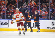 Calgary Flames' Mikael Backlund (11) skates to the bench as Edmonton Oilers' Cody Ceci (5) and Derek Ryan (10) celebrate a goal during the first period of an NHL hockey game Saturday, Oct. 16, 2021, in Edmonton, Alberta. (Jason Franson/The Canadian Press via AP)