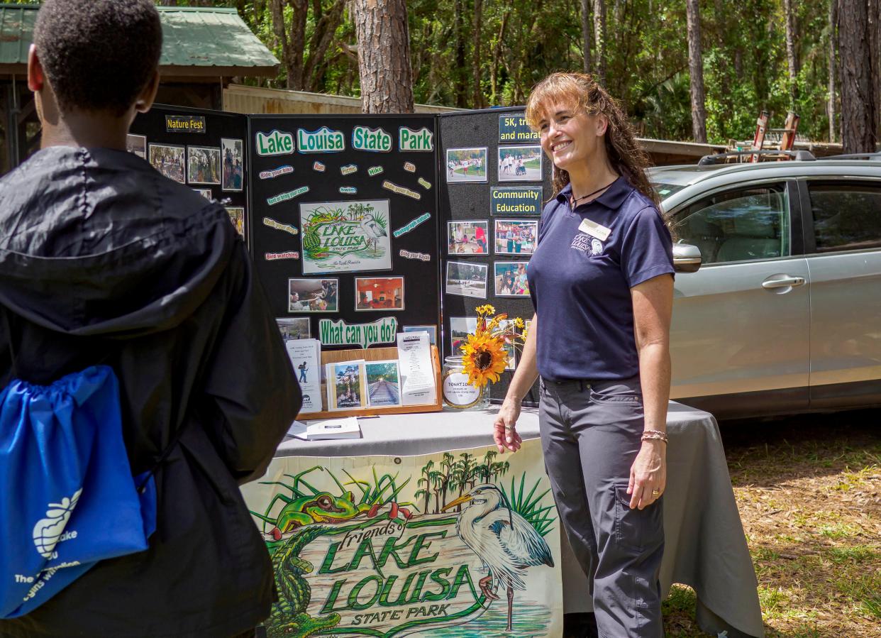 Christy Conk with Friends of Lake Louisa State Park talks with a student at a conservation symposium hosted by Trout Lake Nature Center in Eustis on Saturday, April 30, 2022. [PAUL RYAN / CORRESPONDENT]