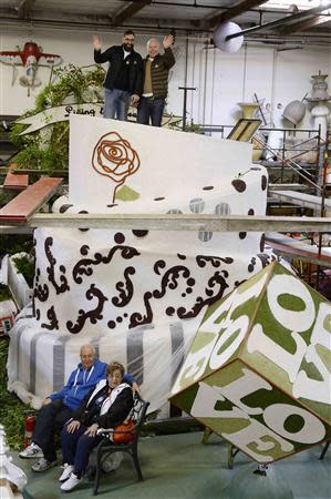 Danny Leclair (L) and Aubrey Loots stand on top of the wedding cake on the AIDS Healthcare Foundation (AHF) Tournament of Roses Parade parade float as Danny's parents Hakim Malouf (bottom, left) and Nouhad Leclair rest on a bench, at Fiesta Parade Floats in Irwindale, California December 30, 2013. REUTERS/Kevork Djansezian