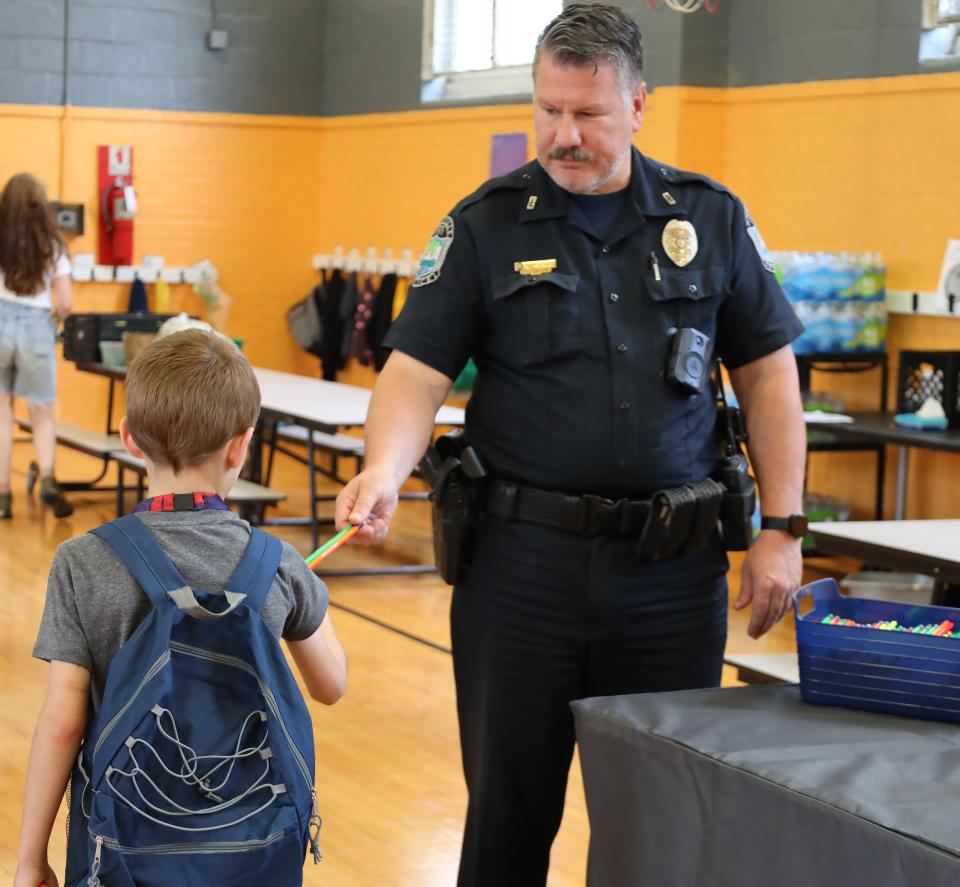 KPD officer Shawn Peoples hands out pencils at the Western Heights community’s back-to-school block party on Aug. 1, 2023.