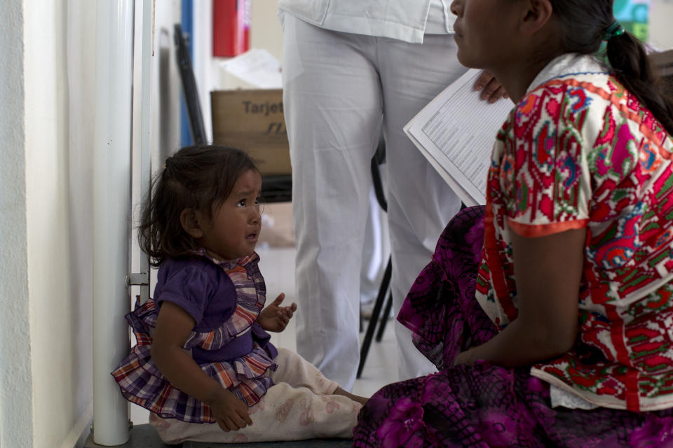 In this Feb. 11, 2014 photo, a woman watches as her child is weighed during their monthly visit to a health clinic in Cochoapa El Grande, Mexico. In the 400 poorest and most malnourished of the country’s 2,400 municipalities, that include Cochoapa, the Mexican government has been trying to enroll more people in existing social programs such as Opportunities, which provides a small monthly stipend to qualifying poor Mexicans, as long as they meet requirements, such as taking their children to the monthly clinic visits. (AP Photo/Dario Lopez-Mills)