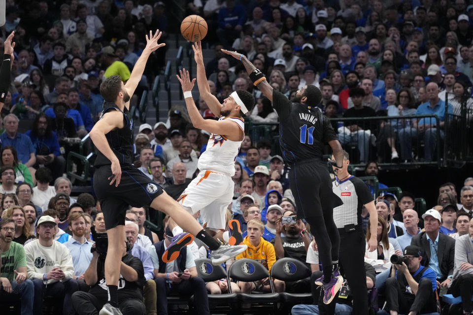 Phoenix Suns guard Devin Booker, center, attempts to shoot as Dallas Mavericks' Maxi Kleber, left, and Kyrie Irving (11) defend in the second half of an NBA basketball game in Dallas, Thursday, Feb. 22, 2024. (AP Photo/Tony Gutierrez)