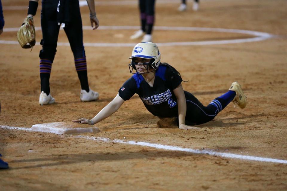 Wellington softball's Angelina Mangini (2) slides safely against Palm Beach Gardens on Friday, March 1, 2024.