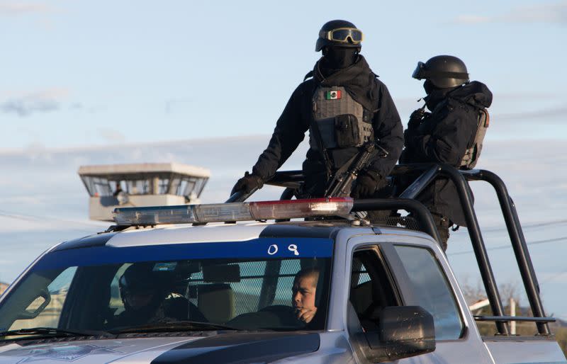 Police officers stand atop a vehicle as they keep watch outside in a prison after sixteen inmates were killed and five were wounded in a prison fight at the Regional Center for Social Reintegration in the town of Cieneguillas