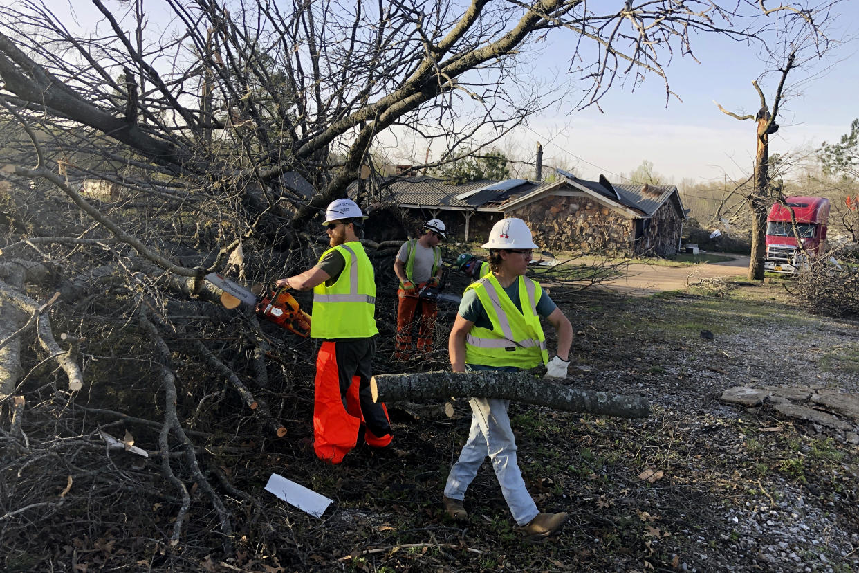 Workers cut fallen trees along a road leading to Wynne, Ark., on Saturday, April 1, 2023. Unrelenting tornadoes that tore through parts of the South and Midwest that shredded homes and shopping centers. (AP Photo/Adrian Sainz)