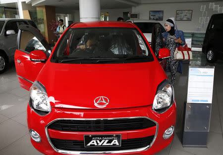 Customers look at a Daihatsu Ayla car at a Daihatsu showroom in Jakarta, November 11, 2014. REUTERS/Beawiharta
