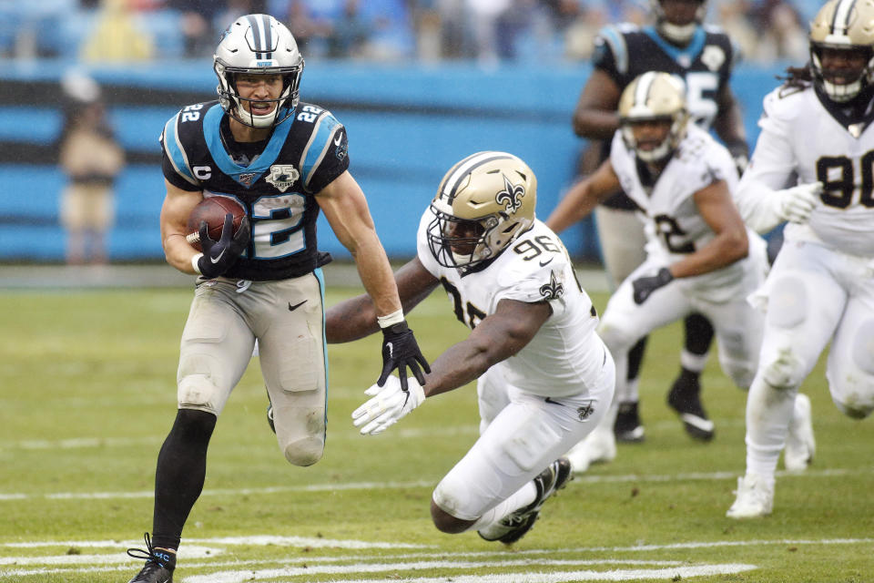 Carolina Panthers running back Christian McCaffrey (22) runs as Carl Granderson (96) reaches for the tackle during the second half of an NFL football game in Charlotte, N.C., Sunday, Dec. 29, 2019. McCaffrey broke a record on the play to become the third player in NFL history to tally 1000 rushing and 1000 receiving yards in the same season. (AP Photo/Brian Blanco)