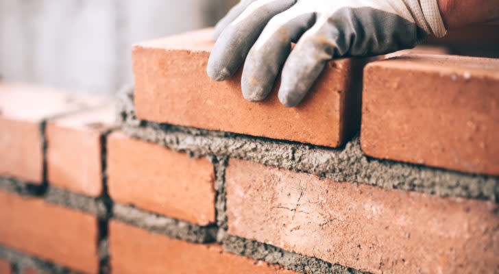 Close up of industrial bricklayer installing bricks on construction site. materials stocks