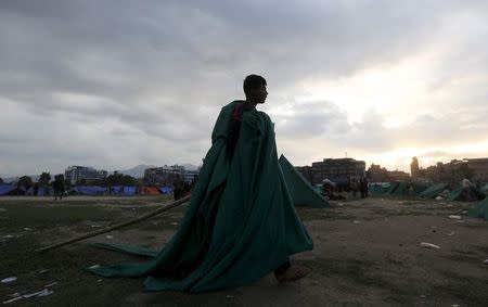 A boy carries bamboos and cloth to built a makeshift shelter at an open ground after an earthquake in Kathmandu, Nepal April 26, 2015. REUTERS/Adnan Abidi