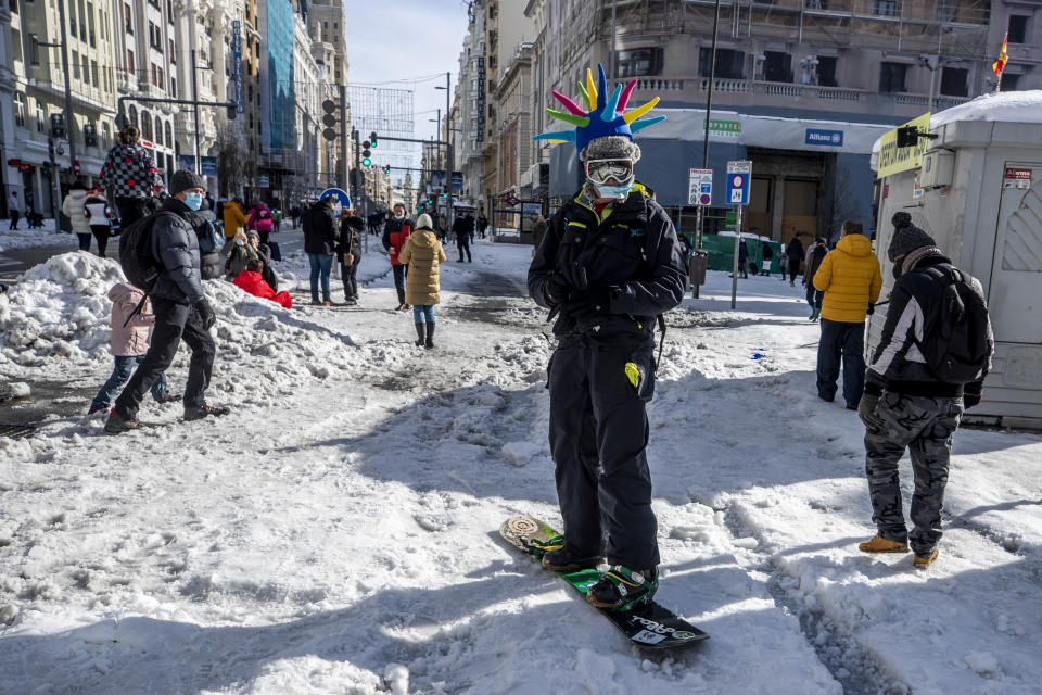 A man snowboards at the Gran Via avenue in downtown Madrid, Spain, Sunday, Jan. 10, 2021. A large part of central Spain including the capital of Madrid are slowly clearing snow after the country's worst snowstorm in recent memory. (AP Photo/Manu Fernandez)