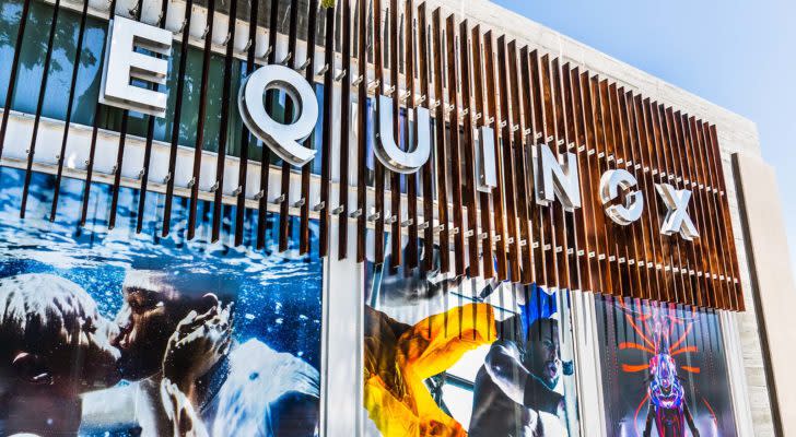 A close-up photo of an Equinox sign with colorful posters on the windows.