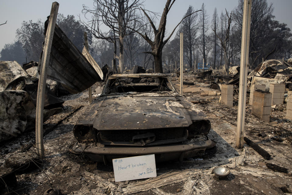 A sign that reads "Heart broken" is displayed in front of a destroyed vehicle at Coleman Creek Estates mobile home park in Phoenix, Ore., Thursday, Sept. 10, 2020. The area was destroyed when a wildfire swept through on Tuesday, Sept. 8. (AP Photo/Paula Bronstein)