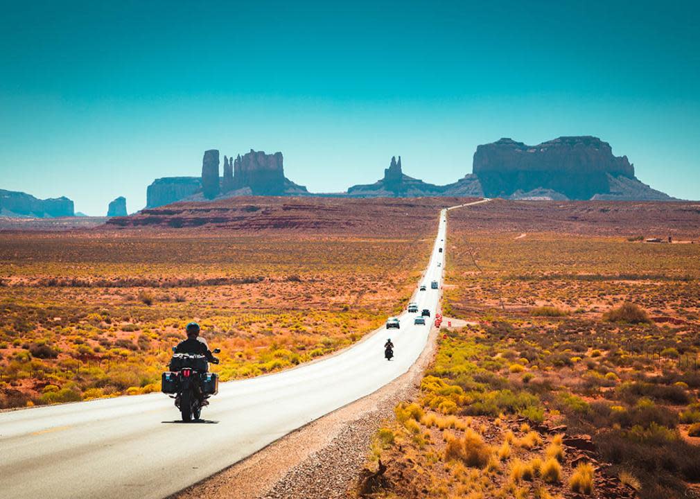 Classic panorama view of motorcyclist on road in moab headed toward monument valley 