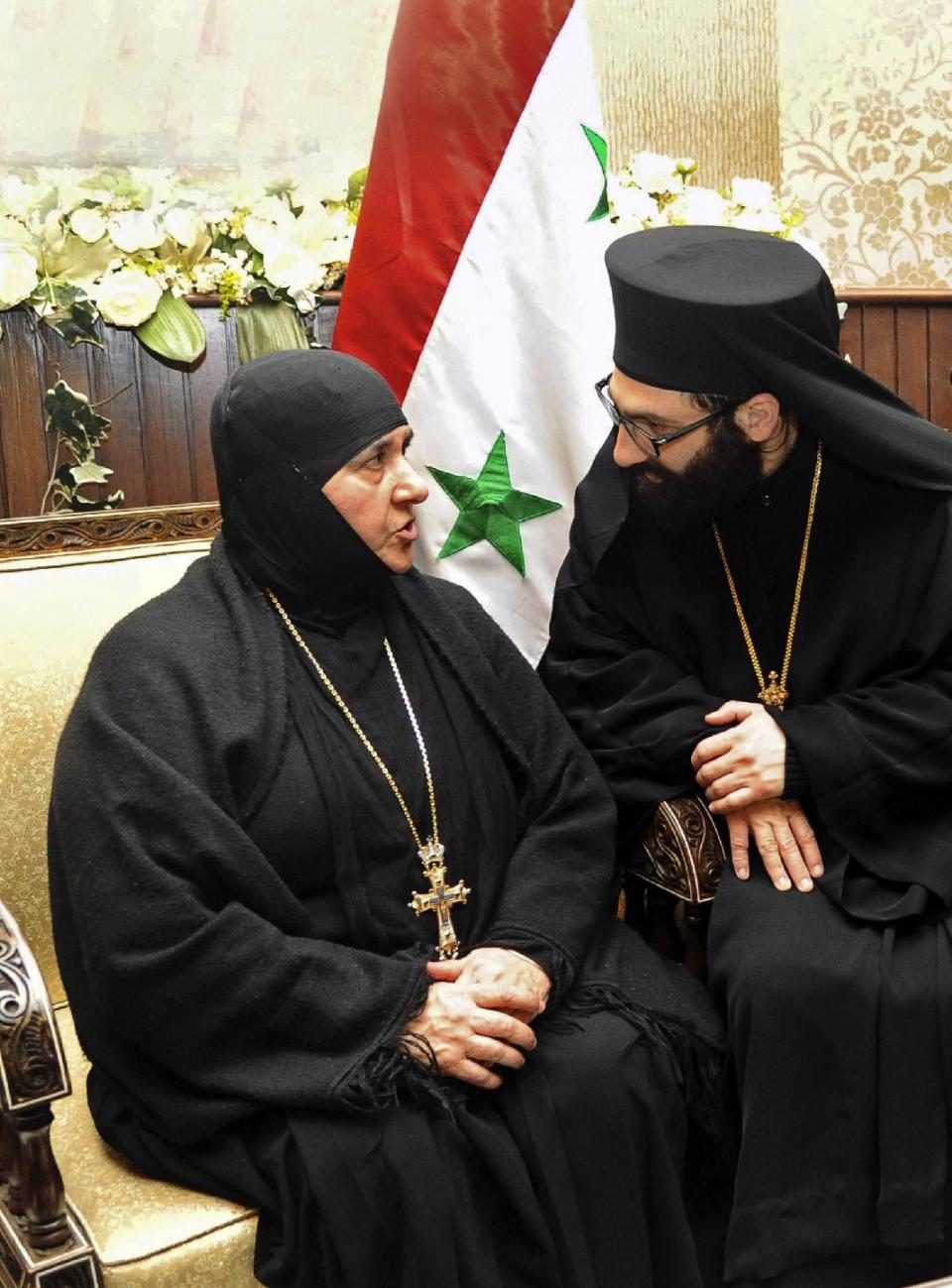 In this photo released by the Syrian official news agency SANA, a nun who was freed after being held by Syrian rebels, is greeted by a church official at the Syrian border town of Jdeidat Yabous, early Monday, March. 10, 2014. Rebels in Syria freed more than a dozen Greek Orthodox nuns on Monday, ending their three-month captivity in exchange for Syrian authorities releasing dozens of female prisoners. The release of the nuns and their helpers, 16 women in all, is a rare successful prisoner-exchange deal between Syrian government authorities and the rebels seeking to overthrow the rule of President Bashar Assad. (AP Photo/SANA)