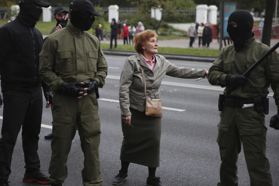 An elderly woman argues with plainclothes policemen during an opposition rally to protest the official presidential election results in Minsk, Belarus, Monday, Oct. 12, 2020. Riot police clashed with protesting pensioners in central Minsk on Monday. The pensioners marched in a column through central Minsk, carrying flowers and posters with slogans such as "The grandmas are with you (protesters)." AP Photo)