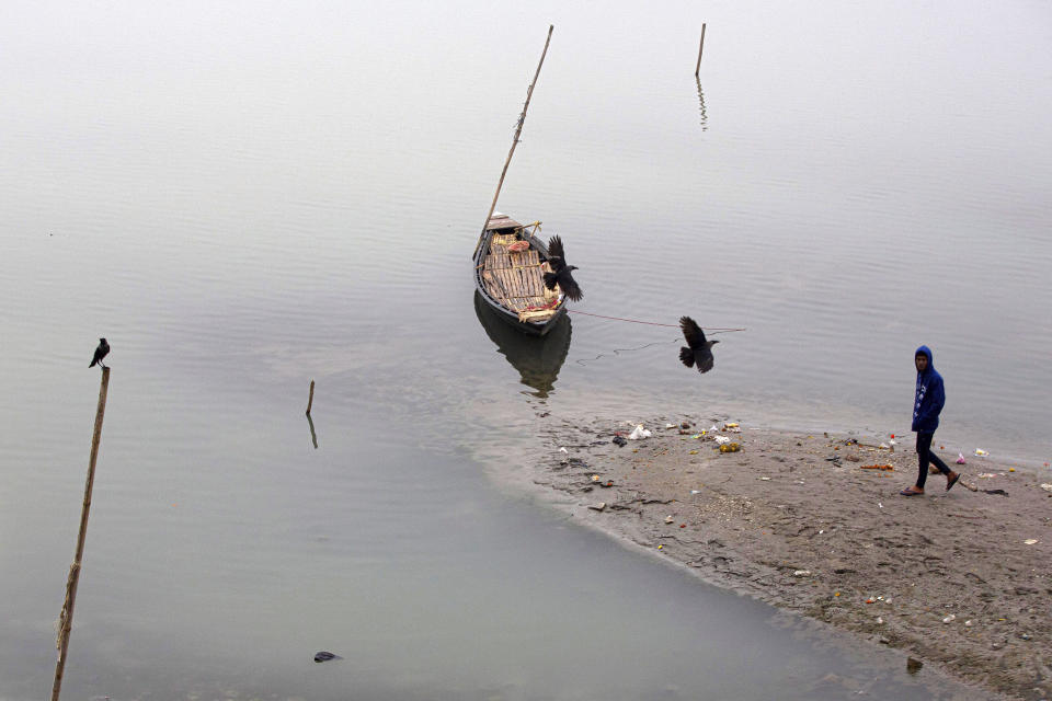 Birds fly over an anchored boat in the river Brahmaputra on a cold winter morning in Gauhati, India, Friday, Jan. 3, 2020. Brahmaputra is one of Asia's largest rivers, which passes through China's Tibet region, India and Bangladesh before converging into the Bay of Bengal. (AP Photo/Anupam Nath)