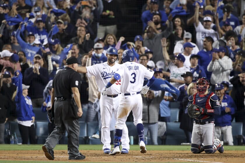 Los Angeles, CA - October 21: Los Angeles Dodgers' Chris Taylor, center, celebrates with Albert Pujols, left, after a two-run home run as Atlanta Braves catcher Travis d'Arnaud looks on during the fifth inning in game five in the 2021 National League Championship Series at Dodger Stadium on Thursday, Oct. 21, 2021 in Los Angeles, CA. (Luis Sinco / Los Angeles Times)