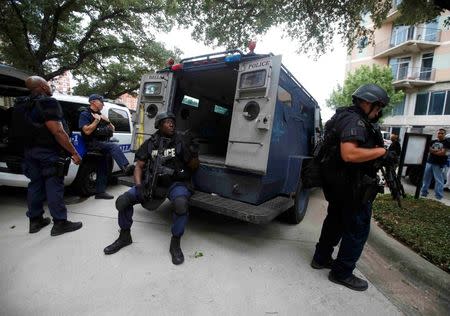 Dallas police SWAT team members stay in a holding position in front of the Dallas Police Department headquarters which was locked down after an anonymous threat was reported in Dallas, Texas, U.S. July 9, 2016. REUTERS/Carlo Allegri