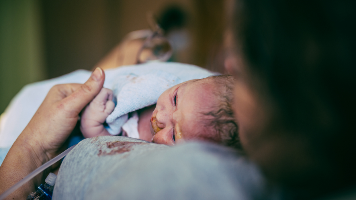 A mother holds her child for the first time after giving birth to her babies.