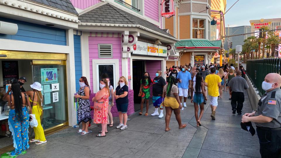 Tourists wearing masks wait in line in Las Vegas on August 28, 2020.