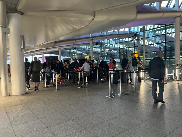 Passengers with checked luggage lined up outside Heathrow's Terminal 2.