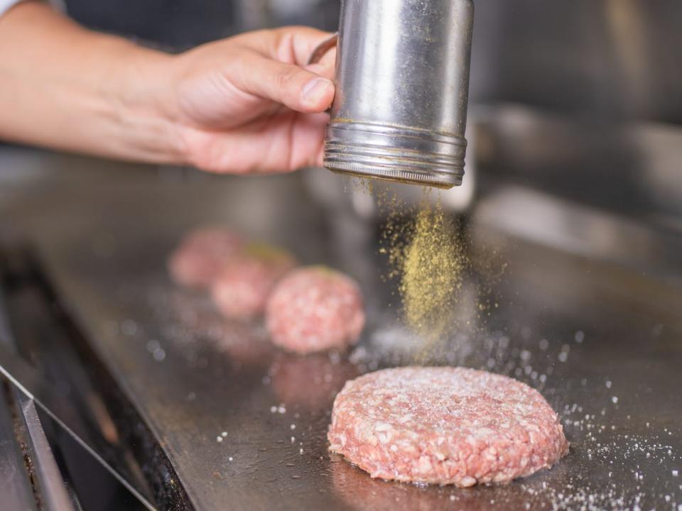 Chef peppering burgers while frying them in the restaurant kitchen