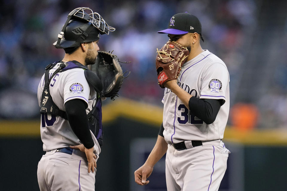 Colorado Rockies staring pitcher Dinelson Lamet, right, gets a visit from Rockies catcher Austin Wynns, left, during the second inning of a baseball game against the Arizona Diamondbacks Wednesday, May 31, 2023, in Phoenix. (AP Photo/Ross D. Franklin)