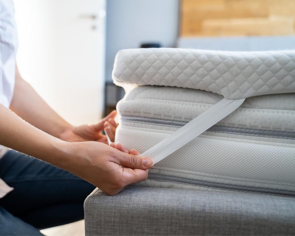 Mattress topper on mattress with lady holding the corner over the bed