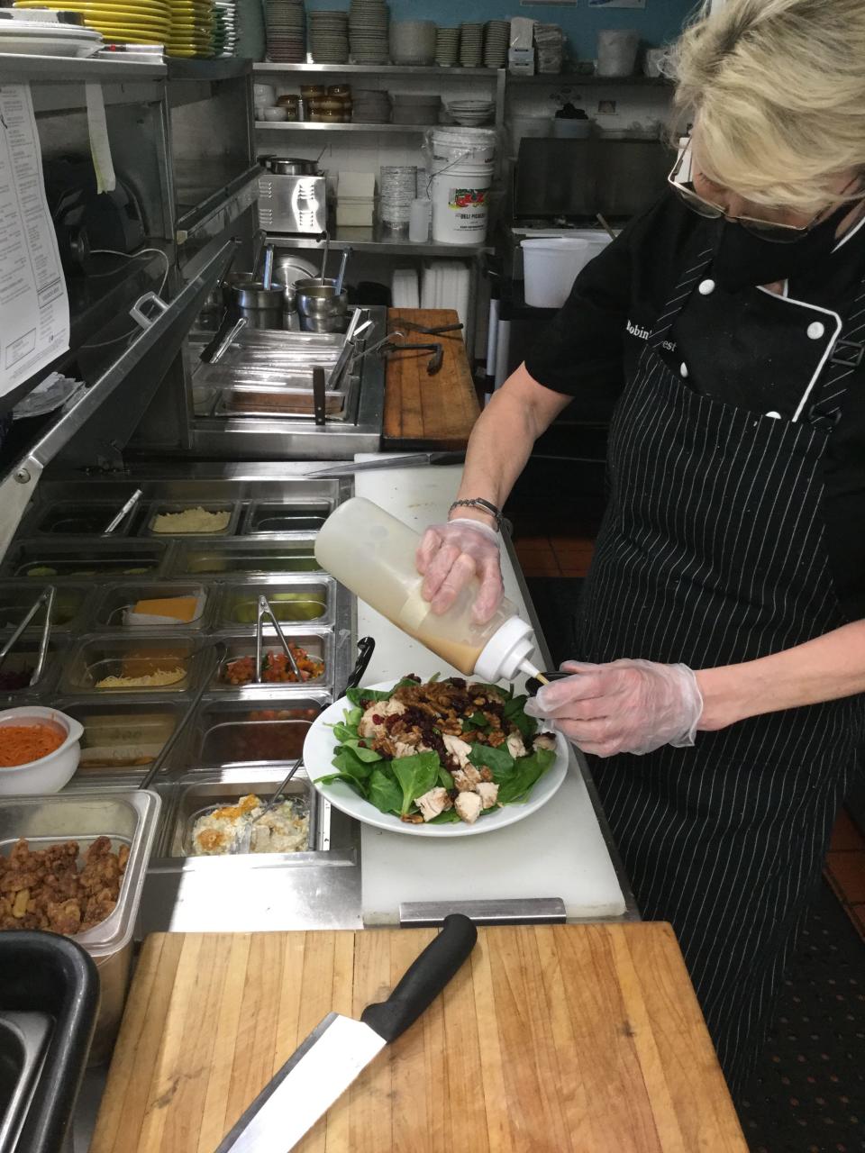 Robin Winzinger dresses a chicken and spinach salad at her Robin's Nest Restaurant in Mount Holly. She buys fresh greens and vegetables when they are in season at Burlington County farms in South Jersey.