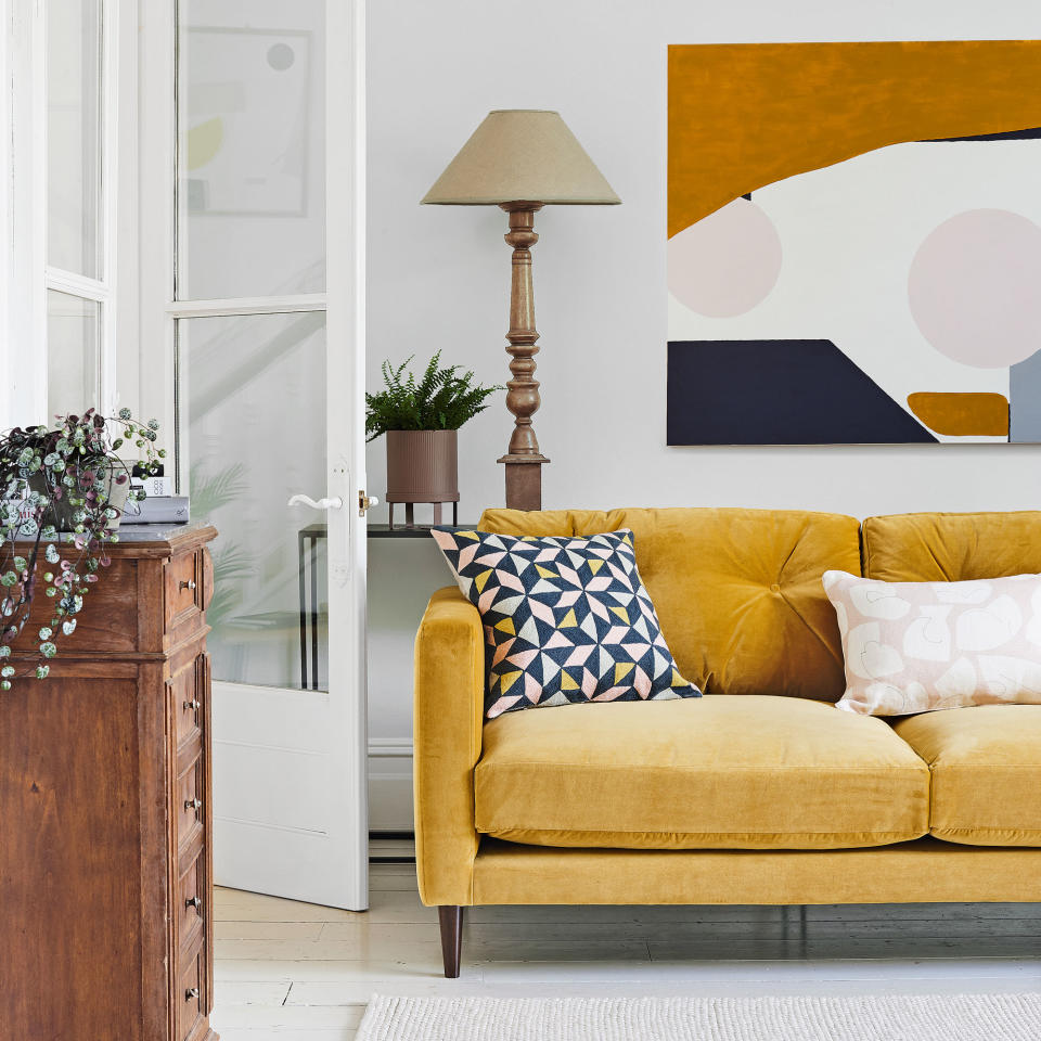 mustard  sofa with large abstract artwork and wooden table lamp