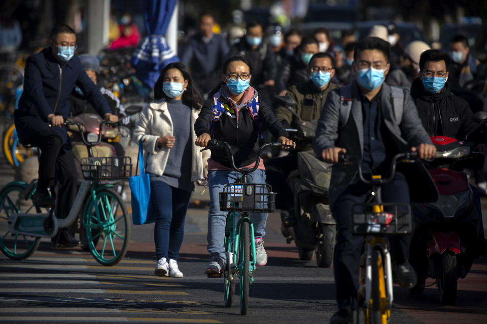 Commuters wearing face masks to protect against the coronavirus ride bicycles across an intersection in Beijing, Thursday, Oct. 22, 2020. The number of confirmed COVID-19 cases across the planet has surpassed 40 million, but experts say that is only the tip of the iceberg when it comes to the true impact of the pandemic that has upended life and work around the world. (AP Photo/Mark Schiefelbein)
