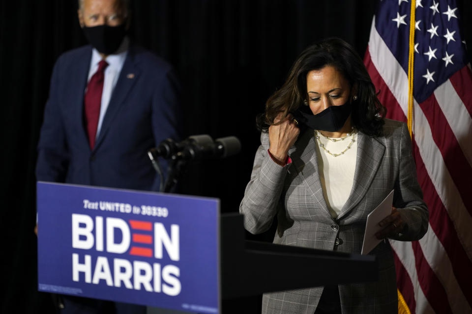 Democratic presidential candidate former Vice President Joe Biden, left, looks on as his running mate Sen. Kamala Harris, D-Calif., removes her face mask to speak at the Hotel DuPont in Wilmington, Del., Thursday, Aug. 13, 2020. (AP Photo/Carolyn Kaster)