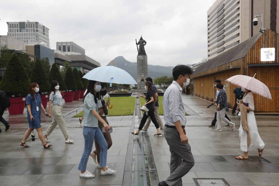 People wearing face masks to help protect against the spread of the coronavirus cross a road in Seoul, South Korea, Thursday, Aug. 27, 2020. South Korea reported more than 400 new cases of the coronavirus, its highest single-day total in months, making lockdown-like restrictions look inevitable as transmissions slip out of control. (AP Photo/Ahn Young-joon)