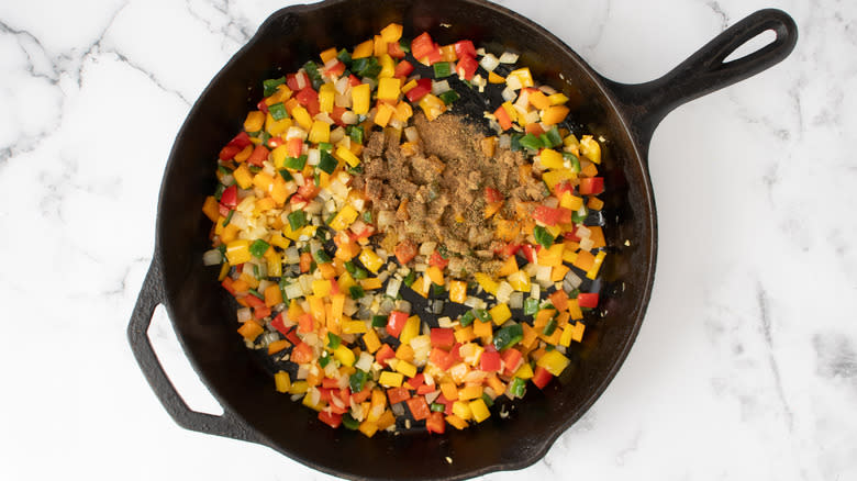 spices added to veggies in skillet