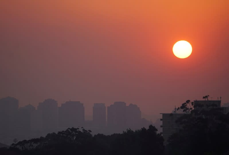 FILE PHOTO: High-rise buildings are seen through smoke from bushfires during sunset in Sydney