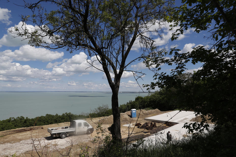 A workers walks at the construction site near Lake Balaton on the peninsula of Tihany, Hungary - a UNESCO world heritage site - on May 18, 2021. Lake Balaton is the largest lake in Central Europe and one of Hungary's most cherished natural treasures. But some worry that the lake's fragile ecosystem and the idyllic atmosphere of the quaint villages dotted along its banks are in danger because of speculative developments. (AP Photo/Laszlo Balogh)