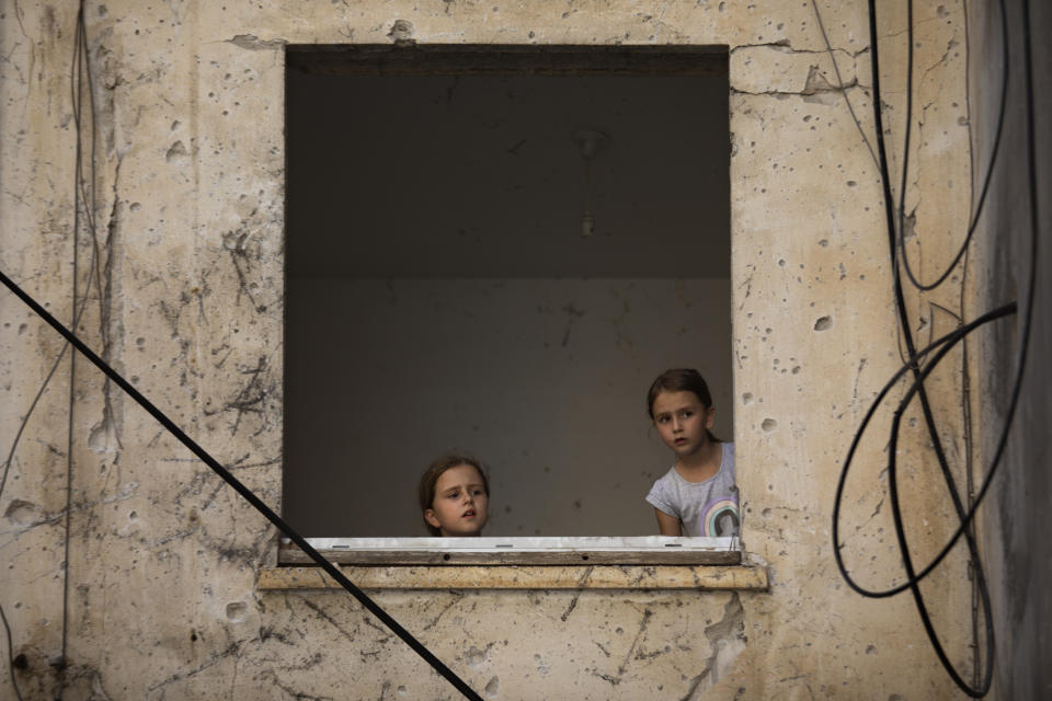 Arina Klochkov, 7, right, and her sister Zoya visit their damaged home after last week it was hit by a rocket fired from the Gaza Strip, in Petah Tikva, central Israel, Friday, May 21, 2021. A cease-fire took effect early Friday after 11 days of heavy fighting between Israel and Gaza's militant Hamas rulers that was ignited by protests and clashes in Jerusalem. (AP Photo/Oded Balilty)