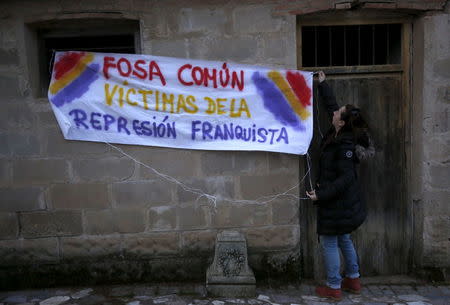 A woman holds a banner that reads "Mass grave victims of late Spanish dictator Francisco Franco's repression" during the exhumation of a grave at Guadalajara's cemetery, Spain, January 19, 2016. REUTERS/Juan Medina