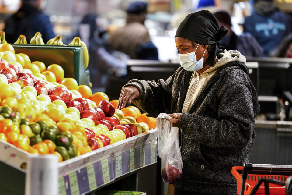 A shopper waring a proactive mask as a precaution against the spread of the coronavirus selects fruit at the Reading Terminal Market in Philadelphia, Wednesday, Feb. 16, 2022. Philadelphia city officials lifted the city's vaccine mandate for indoor dining and other establishments that serve food and drinks, but an indoor mask mandate remains in place. Philadelphia Public Health officials announced that the vaccine mandate was lifted immediately Wednesday. (AP Photo/Matt Rourke)