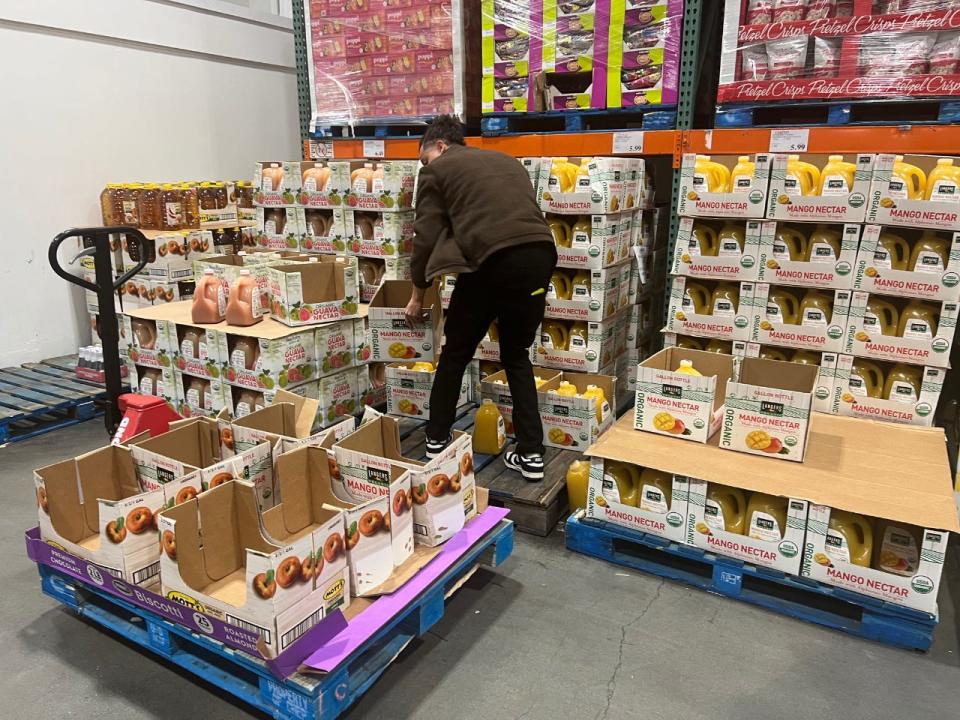 A Costco employee clearing reorganizing stacks of boxes.