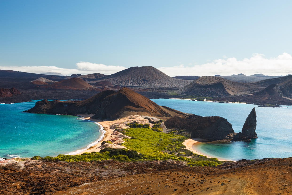 Travel deals in 2024 include Galapagos Islands. Here's a view on the volcanic landscape of Bartolome Island with famous Pinnacle Rock and Golden Beach, Galapagos. (Getty Creative)