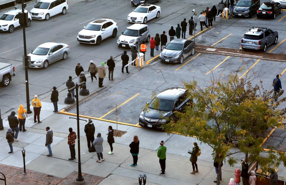 Voters wait in line to cast their ballots, while maintaining social distance, in Des Moines, Iowa, October 30, 2020.