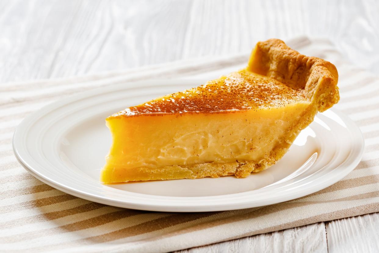 slice of classic sugar cream pie, hoosier pie, indiana custard cream pie on white plate on white wood table, horizontal view from above